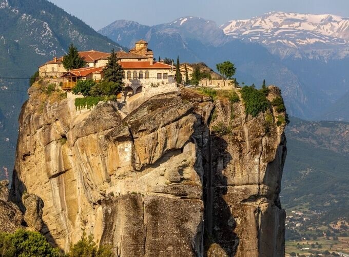 Towering Meteora cliffs with monasteries surrounded by rolling green hills