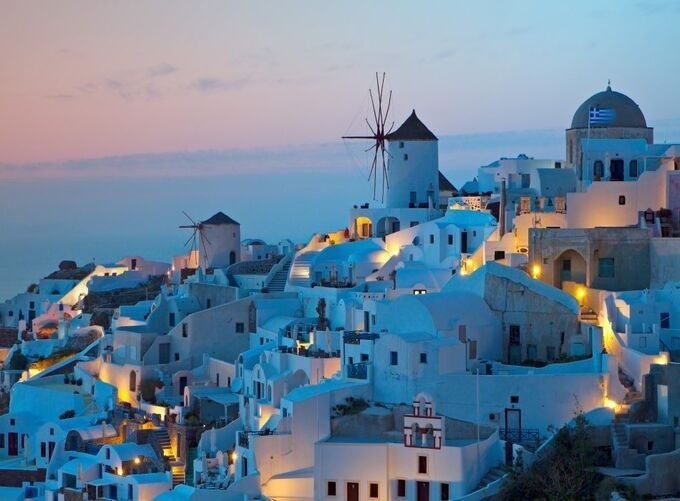 Whitewashed churches and windmills glowing under Santorini’s sunset skies beautifully