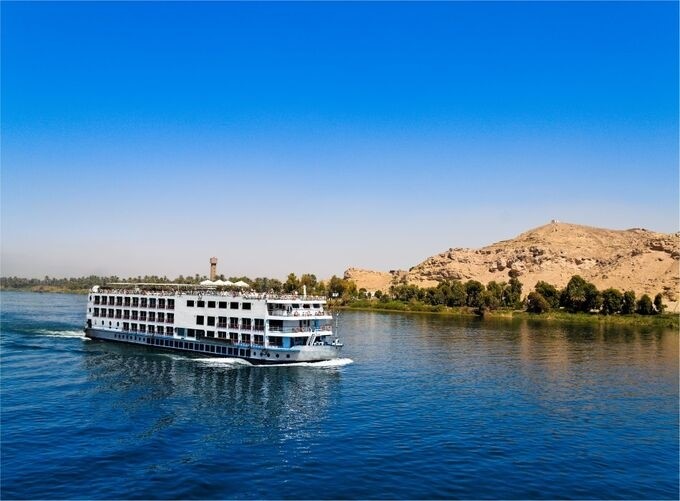 The Nile River reflecting golden sunlight amidst lush green Egyptian scenery