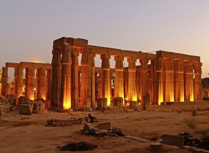 Golden hour illuminating Luxor Temple ruins and surrounding lush greenery