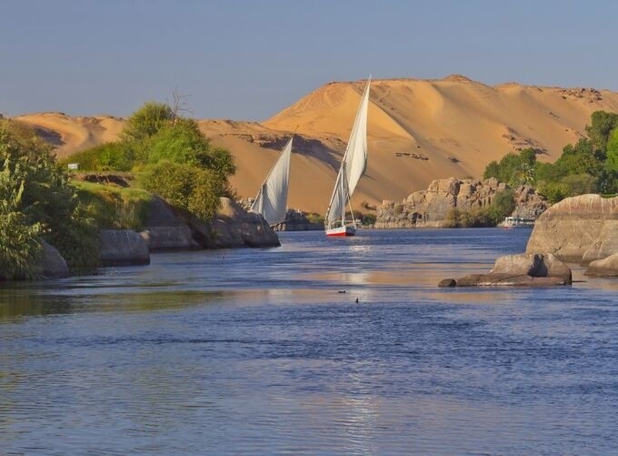 Traditional felucca boat sailing peacefully along the Nile River at sunset