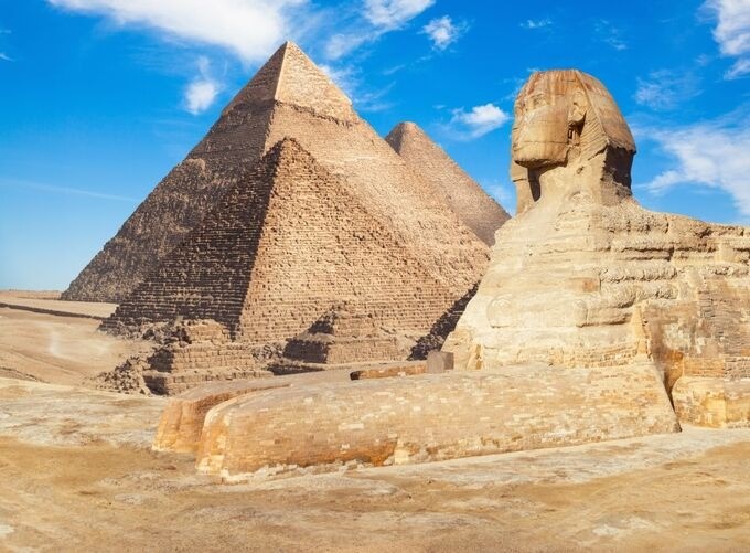 The Sphinx and the Great Pyramid glowing under sunset light