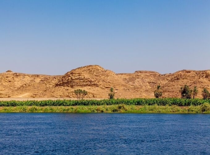 The Nile River surrounded by lush greenery and rocky formations in Aswan