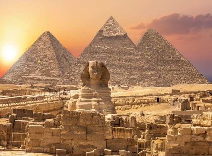 Golden sunlight glowing over the iconic Giza Pyramids and sandy surroundings